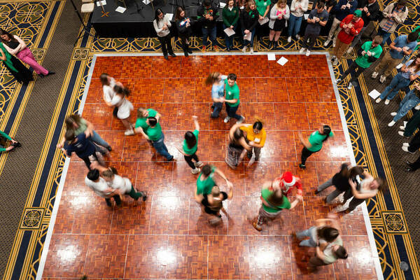 Dance partners on a parquet floor twirl, as seen from above.