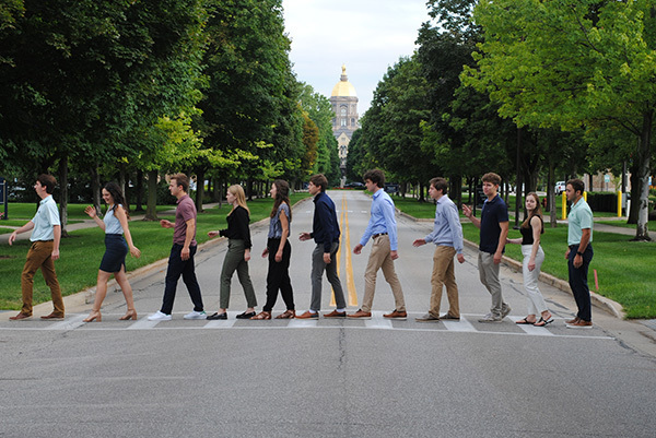Group of students walk across Notre Dame Boulevard in front of Golden Dome.