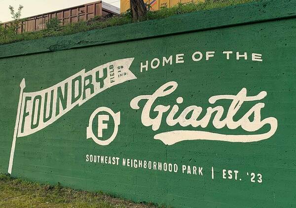 "Foundry Field, Home of the Giants" logo is on a green wall.