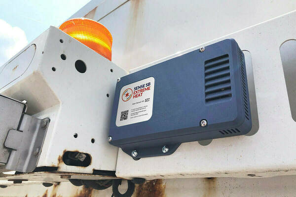 A gray SENSE SB Extreme Heat sensor, labeled "Heat Sensor Kit: 572", mounted on a white garbage truck next to an amber warning light.