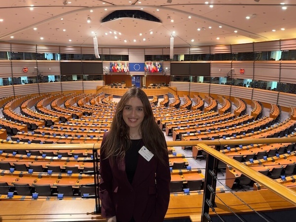 A woman smiling, standing in the gallery overlooking the European Parliament in Brussels, Belgium.