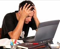 A man sitting in front of a computer with his head in his hands